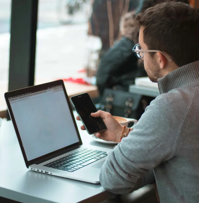 Man looking at laptop screen and mobile phone navigating Nightingale Client Management Software