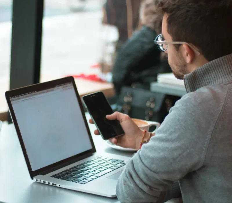Man looking at laptop screen and mobile phone navigating Nightingale Client Management Software